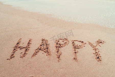 快乐的词手绘在沙滩上的夏日海滩上。