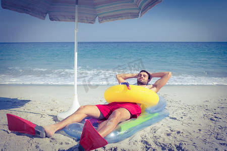 男人躺在沙滩上，带着脚蹼和橡皮圈