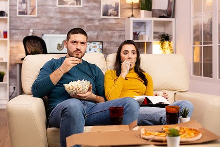 看电视吃快餐外卖的漂亮年轻夫妇