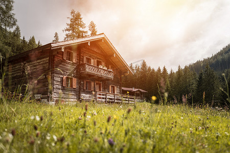 阿尔卑斯山田园诗般的山景：山间小屋、草地和多云的天空