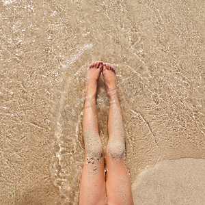 在海滩沙子岸的儿童女孩腿