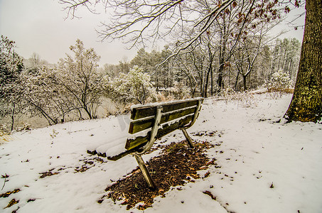 白雪覆盖的公园里的公园长椅，俯瞰着湖泊