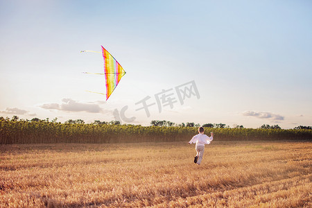风筝玩具摄影照片_农村的一个男孩正在放风筝。