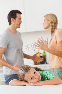 忧郁的女孩摄影照片_一对夫妇在一个悲伤的女孩背后争吵