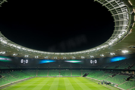 一个开放的足球场，看台上空荡荡的，座位是绿色的。
