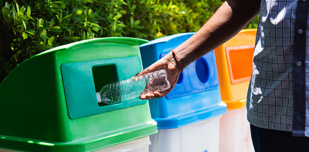 黑手在回收垃圾桶里扔空塑料水瓶
