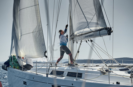 赛拉摄影照片_克罗地亚，地中海，2019 年 9 月 18 日：帆船队关闭船，帆船参加帆船赛，团队工作，拉到绳子、方向盘、彩色大三角帆