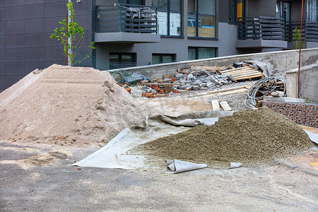 住宅楼摄影照片_一个建筑工地，在一座新住宅楼的背景下，有一堆筛过的沙子和水泥。