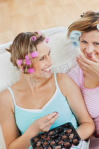 哈哈大笑卡通人物摄影照片_美丽的女性朋友与卷发在 h 吃巧克力