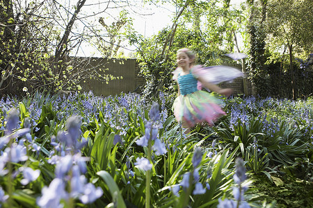 初等摄影照片_穿着仙女服的模糊的小女孩在花园里奔跑