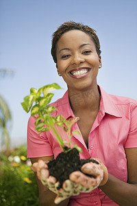 一个快乐的非洲裔美国女人拿着一株植物的画像