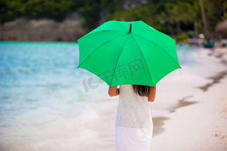 带伞的女孩摄影照片_白色沙滩上带伞的年轻女孩