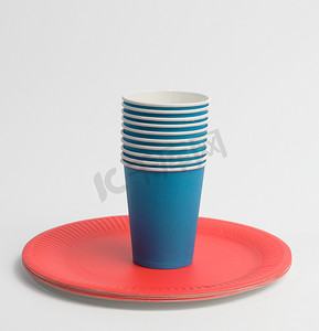 纸杯叠摄影照片_白色背景中的一叠蓝色纸杯和红色圆盘