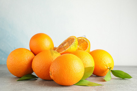浅色背景下灰色桌子上有叶子的成熟橙子，文字空间