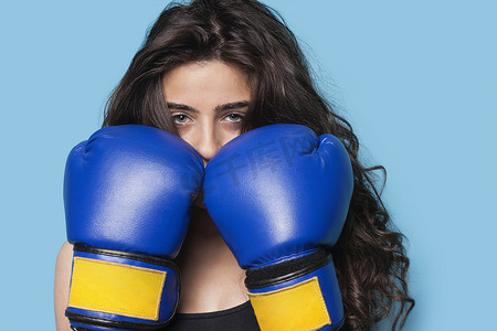 蓝色背景下拳头向上的年轻女拳击手的肖像