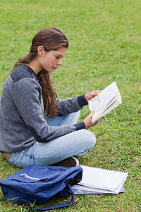 年轻严肃的女孩盘腿坐着看书