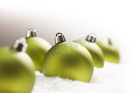 灰色背景下雪地上的绿色圣诞饰品