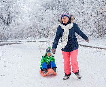 一家人在冬季公园玩雪橇