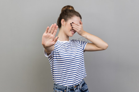 女人用手掌闭上眼睛，摆出停止的手势，转过脸，不想看。