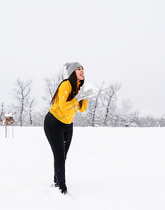 年轻的黑发女人在公园里玩雪