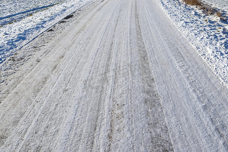 雪街道摄影照片_近距离观察积雪覆盖的街道上的轮胎痕迹。