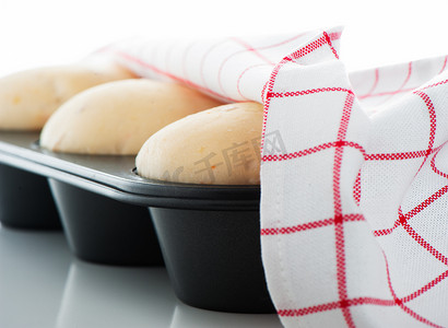 锅饼摄影照片_松饼锅中的酵母面团，白色和红色毛巾