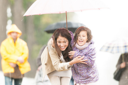 母亲和孩子在雨天的伞下。
