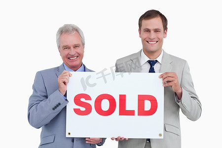 房地产横幅摄影照片_微笑的房地产经纪人举着已售出的牌子