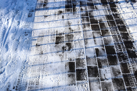 近距离观察积雪覆盖的街道上的轮胎痕迹。