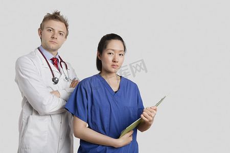 灰色背景下一位白人医生与一位亚洲护士站在一起的肖像