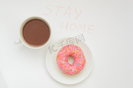 顶视图，一杯可可饮料和一个白色背景的粉红色甜甜圈 甜点 待在温暖的家