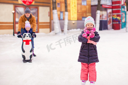 溜冰场上可爱的小女孩，背景是爸爸和可爱的妹妹