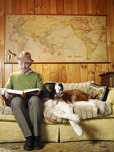 老人坐在沙发上摄影照片_老人坐在沙发上，带着狗看书