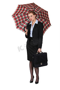 拿着公文包和伞的严肃的女实业家