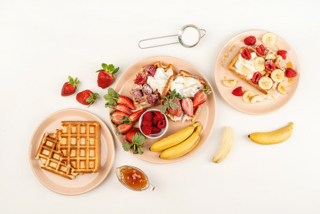 盘子里面放水果摄影照片_白桌上的盘子里放着自制的华夫饼，里面有水果和浆果、奶油和蜂蜜