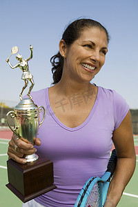 中年女子网球运动员在球场上拿着奖杯前视