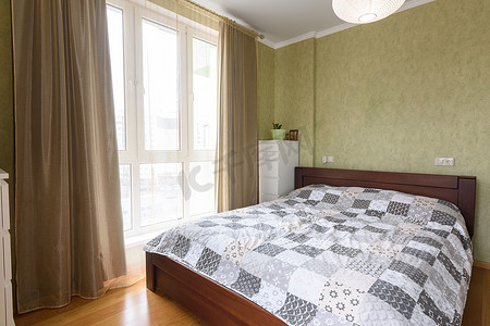 卧室内部配有一张大双人床和一扇带薄纱和窗帘的大彩色玻璃窗
