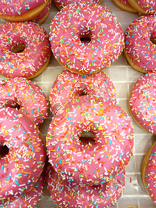 甜甜圈在糖粉色釉中甜甜的，面包店陈列柜。