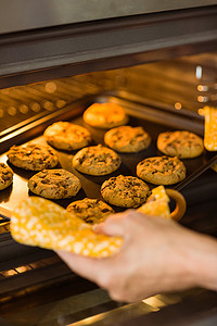 烤箱饼干摄影照片_女人从烤箱里拿出一盘新鲜饼干