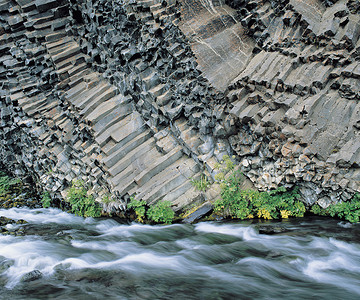 柱状图模板摄影照片_柱状玄武岩悬崖底部的植物和河流