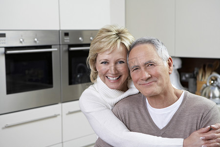 在厨房里微笑的恩爱中年夫妇的特写肖像