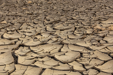 干地摄影照片_干裂的泥沙漠，如灰色背景，有选择地聚焦的焦土
