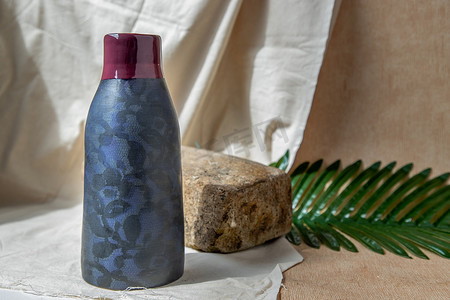 白色纹理桌布上的蓝色和深红色手工陶瓷花瓶。
