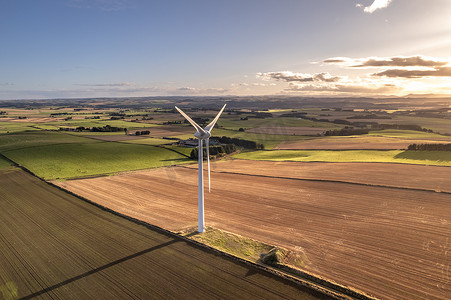 风里发电摄影照片_阳光明媚的日子里，绿色可再生能源农场的风力涡轮机