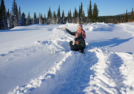 在一个阳光明媚的下午玩雪的女人。
