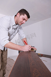 男子在切割成尺寸之前标记镶木地板