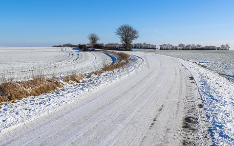 德国阳光明媚的日子里，乡间小路被雪覆盖。