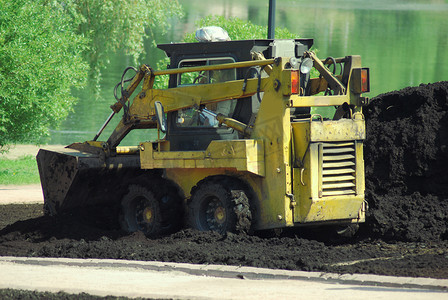 春季在城市公园工作的小型挖掘机抓斗