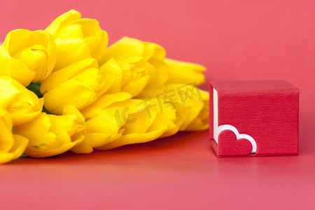 妇女节背景红色摄影照片_一束红色背景上的新鲜黄色郁金香。