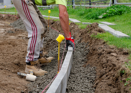 新农村建设摄影照片_新的人行道建设，地基工人/道路工程正在放置 edg